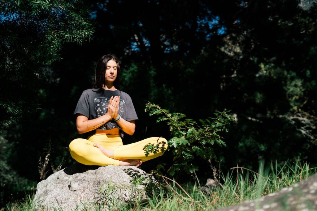 A woman sitting on the rock and doing yoga