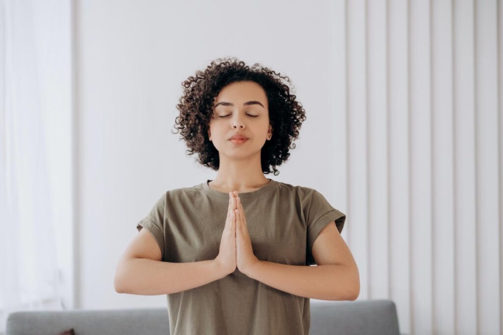 A wooden with her hands joined together as doing yoga