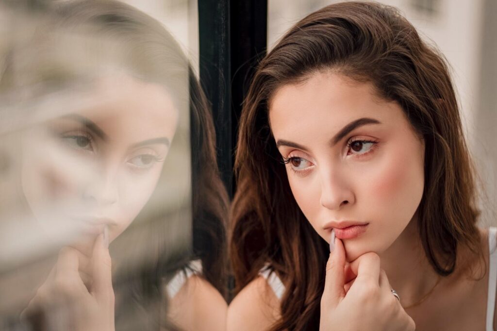 A woman sitting with a window reflecting her