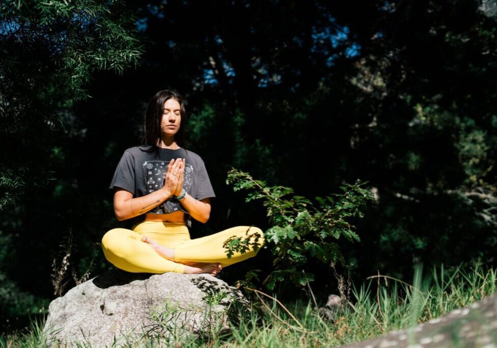 A woman sitting on the rock and doing yoga