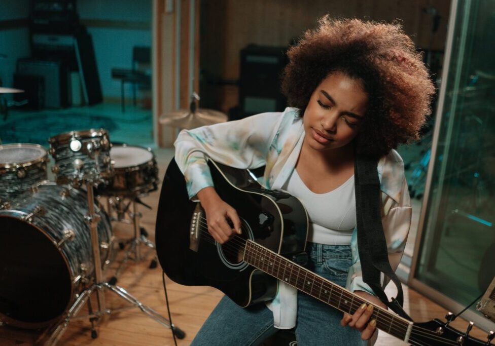 closeup of a woman playing a guitar with eyes closed